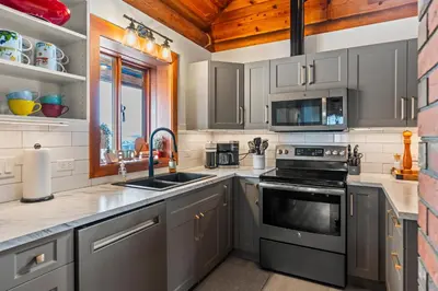 a kitchen with stainless steel appliances and a window at The View Point Lodge Cozy Log House with Hot Tub in Vernon