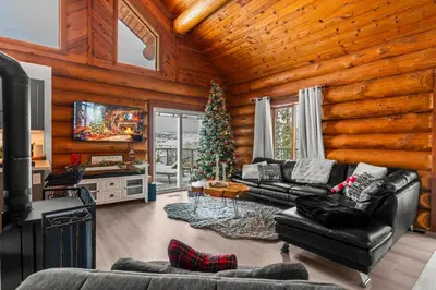 a living room with a christmas tree in a log cabin at The View Point Lodge Cozy Log House with Hot Tub in Vernon