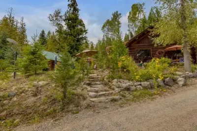 a log cabin with a stone path next to a house at Authentic lofted log cabin with hot tub in Kelowna