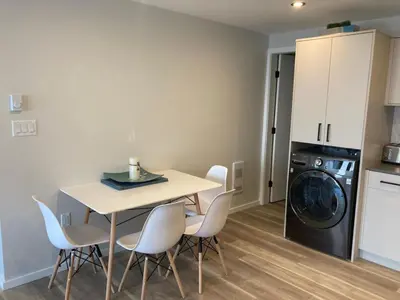 a kitchen with a table and chairs and a washing machine at Lakefront Nest Beach House Suite in Penticton