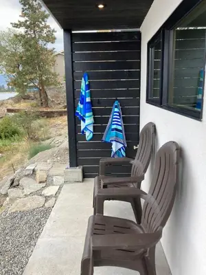 two chairs and an umbrella on the side of a house at Lakefront Nest Beach House Suite in Penticton