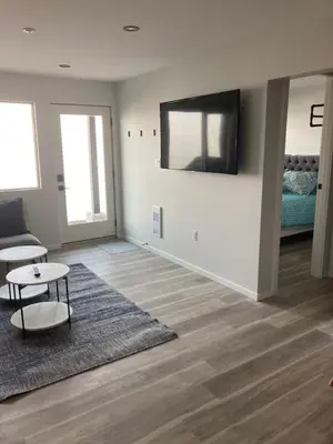 a living room with a couch and a tv on a wall at Lakefront Nest Beach House Suite in Penticton
