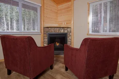 two chairs in a living room with a fireplace at Jasper East Cabins in Jasper