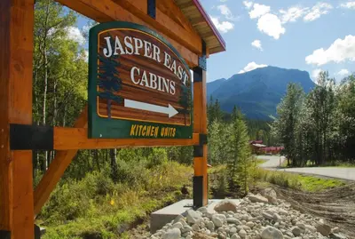 a sign for a jasper pass cabins on a road at Jasper East Cabins in Jasper
