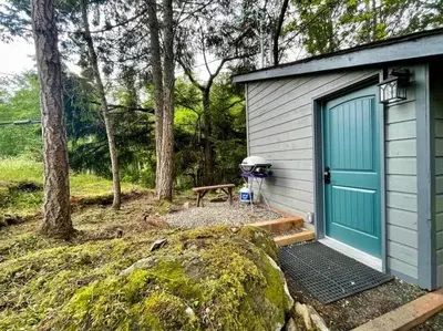 a small shed with a blue door and a picnic table at Cozy Cabana with Large Private Outdoor Hot Tub in Nanoose Bay