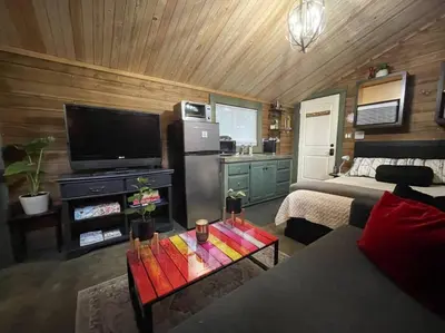 a living room with a couch and a tv and a table at Cozy Cabana with Large Private Outdoor Hot Tub in Nanoose Bay