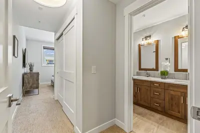 a white bathroom with a sink and a mirror at Elevated Mountain Living 2BD Spring Creek Unit in Canmore