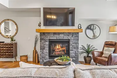 a living room with a fireplace and a tv at Elevated Mountain Living 2BD Spring Creek Unit in Canmore