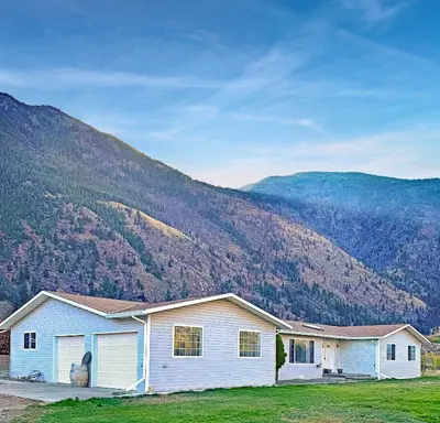 a white house with a mountain in the background at Blush Bliss A Peaceful Vineyard Escape in Keremeos