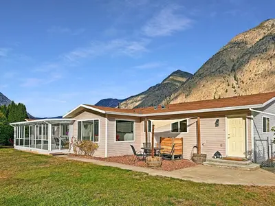 a white house with mountains in the background at Blush Bliss A Peaceful Vineyard Escape in Keremeos