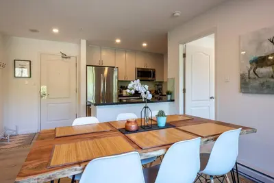 a dining room with a wooden table and white chairs at Location with Views - 2BDR Penthouse Whistler Village in Whistler