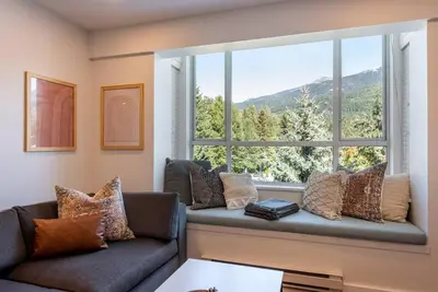 a living room with a couch and a large window at Location with Views - 2BDR Penthouse Whistler Village in Whistler