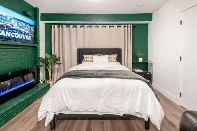 a bedroom with a large bed and a flat screen tv at Vancouver Central Green Studio in Vancouver