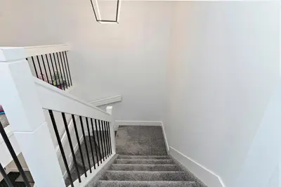 a staircase in a house with white walls at The Happy place - Luxurious, Cozy and Modern Home with 4 bedroom Air-condition, Netflix, Free Parking close to Airport and West Edmonton Mall in Edmonton