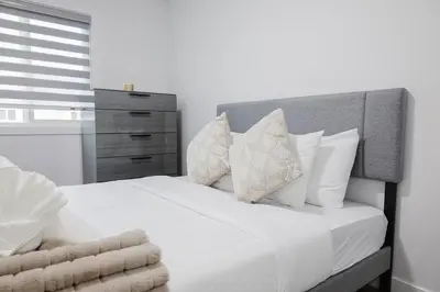 a bedroom with a white bed with pillows and a dresser at Executive Modern Family Haven for Short Stays in Edmonton