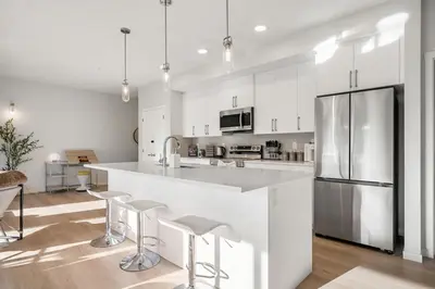 a kitchen with white cabinets and a large island with bar stools at Very Spacious Luxury Apartment with AC, 70