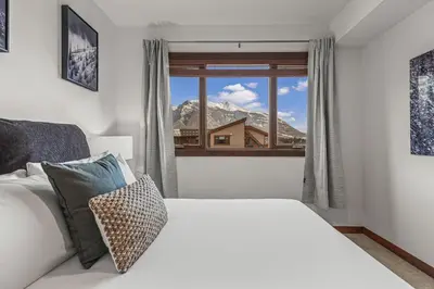 a bedroom with a bed and a window with mountains at Skyline Suite Downtown Canmore Stay in Canmore