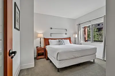 a white bedroom with a bed and a window at Classic Hideaway Elegant 2BD 2BTH in Canmore