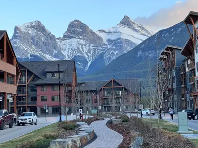 a street in a town with mountains in the background at Chic Urban Sanctuary in the Heart of Down in Canmore