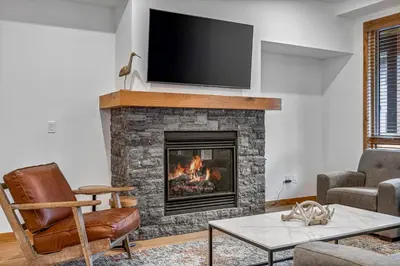 a living room with a fireplace with a flat screen tv at Chic Urban Sanctuary in the Heart of Down in Canmore