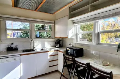 a kitchen with three windows and a table with chairs at Trendy Glenora , Sleeps 10 , Downtown & River Valley adjacent , Jacuzzi tub! in Edmonton