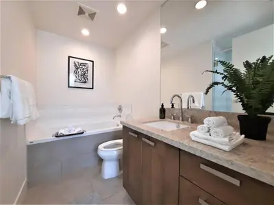 a bathroom with a sink and a toilet and a tub at Luxury Condo by River with City Views in Calgary
