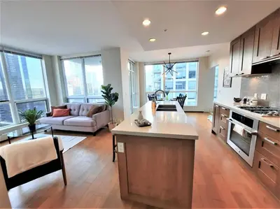 a large kitchen and living room with a couch at Luxury Condo by River with City Views in Calgary