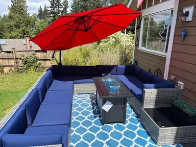 a red umbrella sitting on a blue couch with a table at Bright Spacious Entire Home with Kids Backyard Set in Victoria