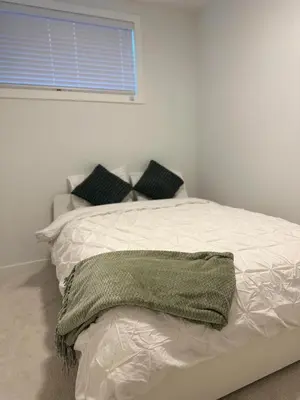 a white bed with a green blanket on top of it at A Cozy Private Suite in Rangeview, SE Calgary in Calgary