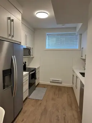 a kitchen with a stainless steel refrigerator and a window at A Cozy Private Suite in Rangeview, SE Calgary in Calgary