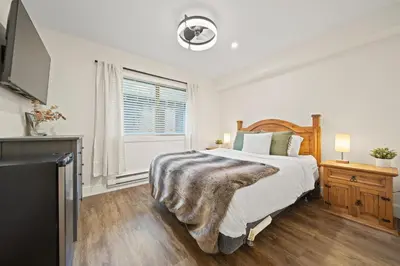 a white bedroom with a bed and a tv at Whistler Lakeside Hideaway in Whistler