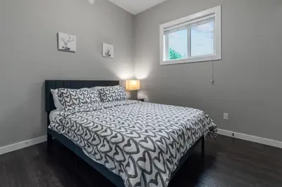a bedroom with a bed with a black and white comforter at Peaceful 2 Bedroom Suite that sleeps 4 with Free Wifi ,Free parking,easily accessible to Downtown Vancouver in Surrey