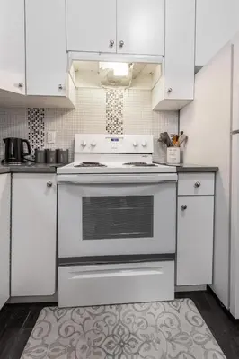 a kitchen with white cabinets and an oven at Peaceful 2 Bedroom Suite that sleeps 4 with Free Wifi ,Free parking,easily accessible to Downtown Vancouver in Surrey