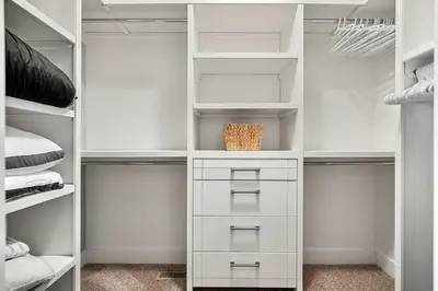 a white walk in closet with white shelves and a basket at Luxury Cityscape Retreat with Hot Tub in Calgary