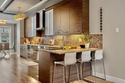 a kitchen with wooden cabinets and white bar stools at Luxury Cityscape Retreat with Hot Tub in Calgary