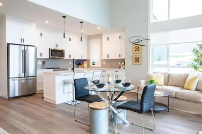 a kitchen and living room with a table and chairs at The Luna, New Penthouse w Patio, Lake and Mtn Views in Harrison Hot Springs