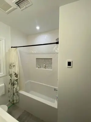 a white bathroom with a tub and a shower at Walk to the beaches and the restaurants downtown! in Kelowna