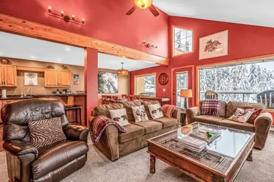 a living room with red walls and leather furniture at Fresh Tracks Retreat - Ski In Out Mtn View & Private Hot Tub in Big White