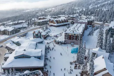 a ski resort with a bunch of people in the snow at Fresh Tracks Retreat - Ski In Out Mtn View & Private Hot Tub in Big White