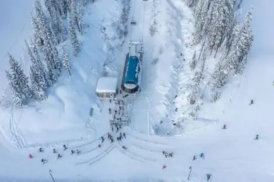 a group of people on a ski lift in the snow at Fresh Tracks Retreat - Ski In Out Mtn View & Private Hot Tub in Big White