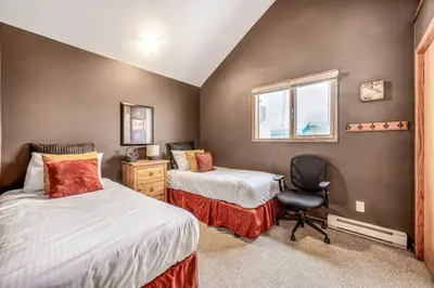a bedroom with two beds and a desk and a window at Fresh Tracks Retreat - Ski In Out Mtn View & Private Hot Tub in Big White