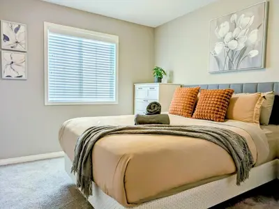 a bedroom with a large bed with orange pillows at A Slice of Heaven in Airdrie by EaglesWingsHomes1 in Airdrie