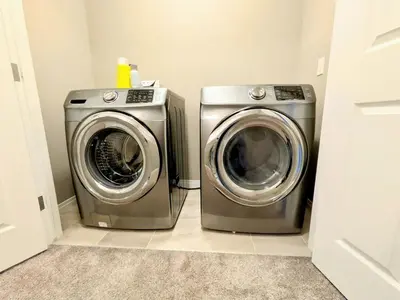 a washing machine and a dryer in a laundry room at A Slice of Heaven in Airdrie by EaglesWingsHomes1 in Airdrie