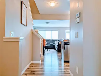 a hallway of a home with a staircase and a living room at A Slice of Heaven in Airdrie by EaglesWingsHomes1 in Airdrie