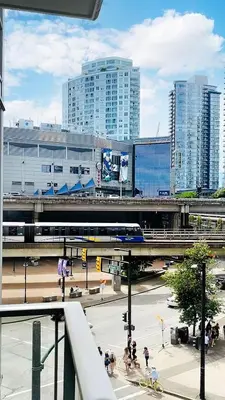 a train on a track in a city with tall buildings at Stylish Condo in Downtown in Vancouver