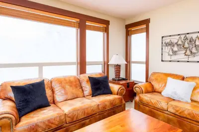 a living room with two leather couches and a table at Stonegate Resort Unit A104 in Big White