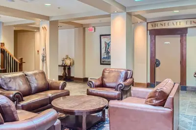 a waiting room with leather chairs and a table at Stonegate Resort Unit A104 in Big White