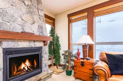 a fireplace in a living room with a stone wall at Stonegate Resort Unit A104 in Big White