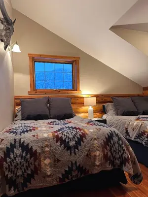 a bedroom with two beds and a window at Ryders Lodge, Log Home in Edgewater, BC in Radium Hot Springs