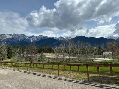 a wooden fence on the side of a road with mountains at Ryders Lodge, Log Home in Edgewater, BC in Radium Hot Springs